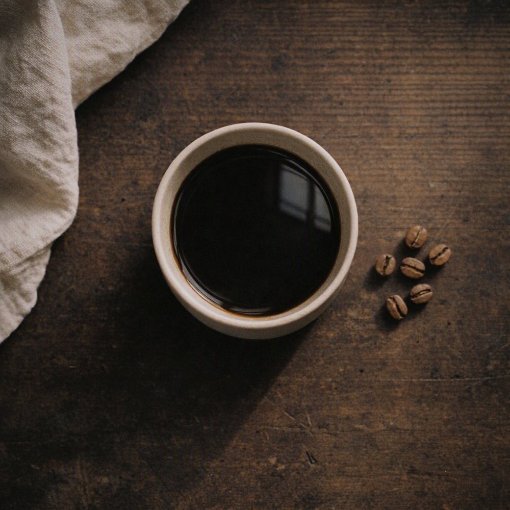 Taza de café negro servida, vista desde arriba sobre madera